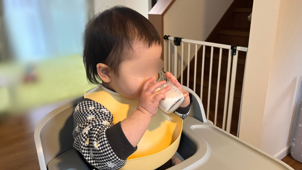 つよいこグラスを自分で掴んで上手に牛乳を飲む子供の様子。